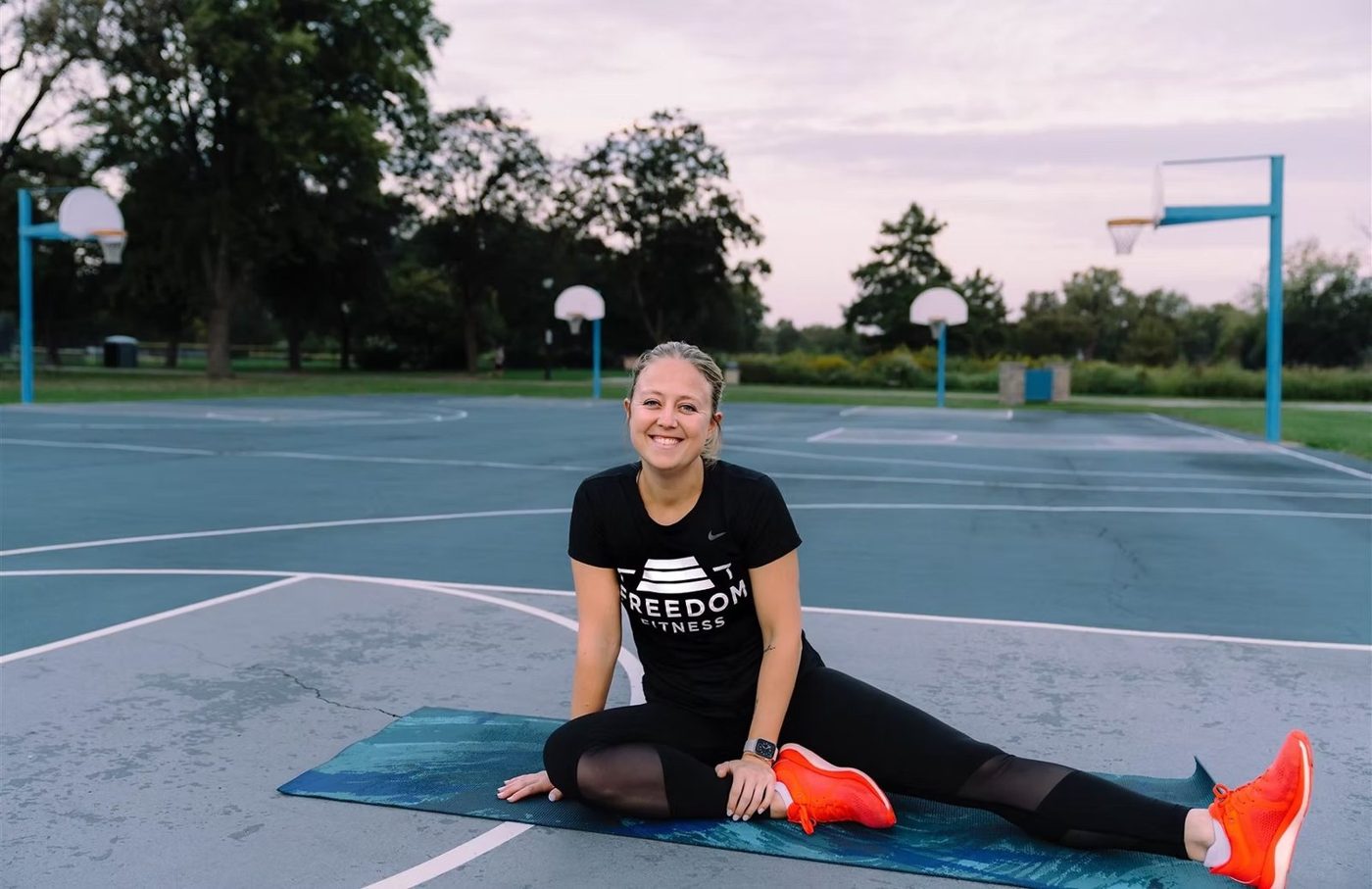 Bri stretching on a mat on an outdoor court